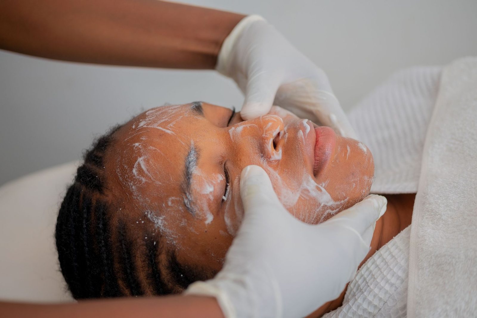 A treatment being worked into the skin with gloved hands, as in SQT Bio-Microneedling